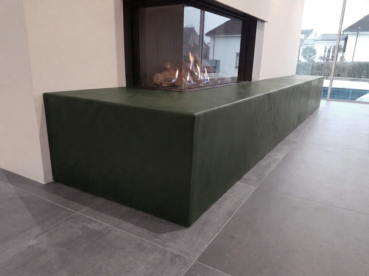 Kamin mit grünem Leder vollflächig verkleidet.